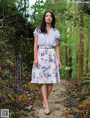 A woman sitting on a rock in the woods.