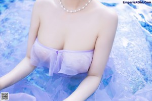 A woman in a pink dress standing next to a pool.