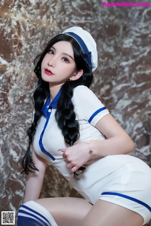 A woman in a white and blue uniform posing for a picture.