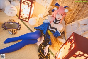 A woman in a blue and black outfit sitting on the floor.