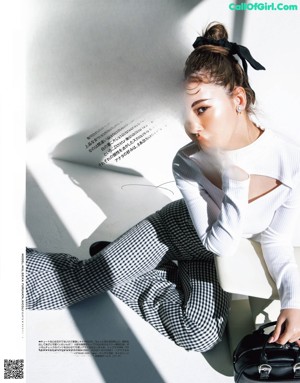 A woman in a black top and skirt posing for a magazine.