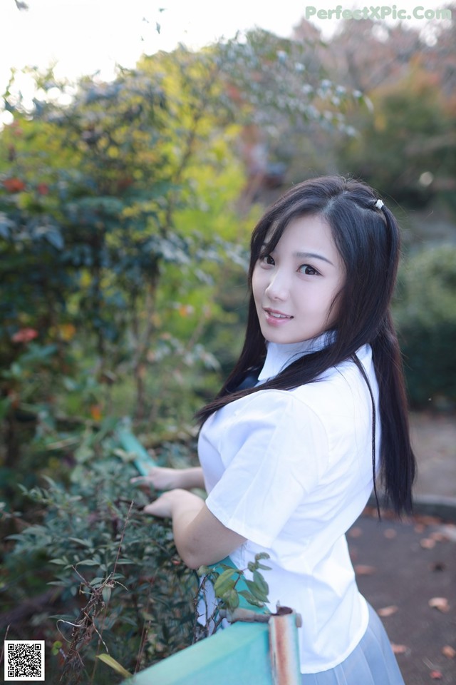 A woman in a white shirt and blue skirt posing for a picture.