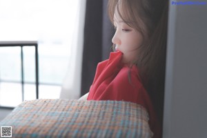 A woman in a red hoodie sitting on a chair.
