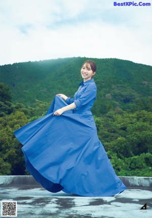 A woman in a blue dress standing on top of a building.
