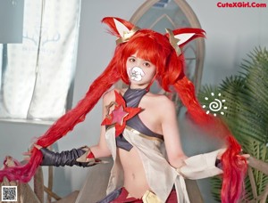 A woman with long red hair sitting on a chair.
