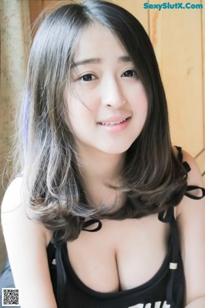 A woman in a black top is sitting on a bed.