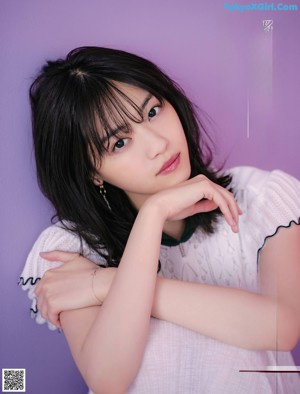 A woman in a white shirt and white pants posing for a magazine.