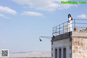 A woman in a black dress standing on a balcony.