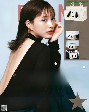 A woman in a black top and white pants posing for a magazine.