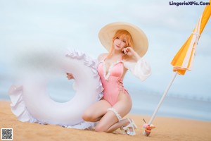 A woman in a pink bikini and white hat on a beach.