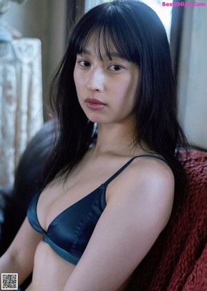 A woman laying on top of a black couch.