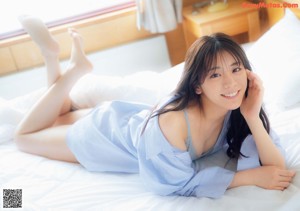 A woman laying on a bed with her legs up.