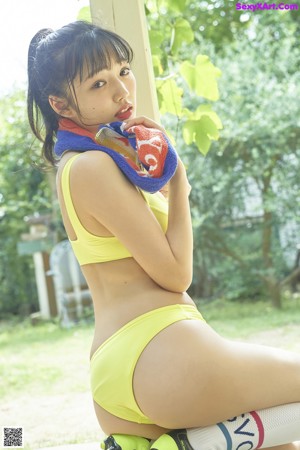 A woman in a yellow bikini holding a bottle of water.