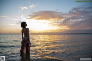 A woman in a pink dress standing on a beach.