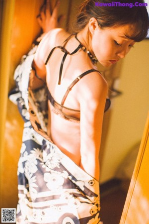 A woman in a kimono sitting on a window sill.