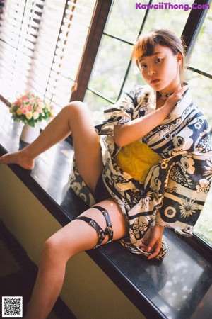 A woman in a kimono leaning against a window sill.