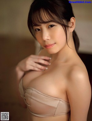 A woman in a white bikini sitting on a bed.